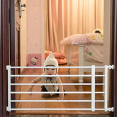 Baby wearing a white hooded outfit climbing behind a home retractable baby gate for safety